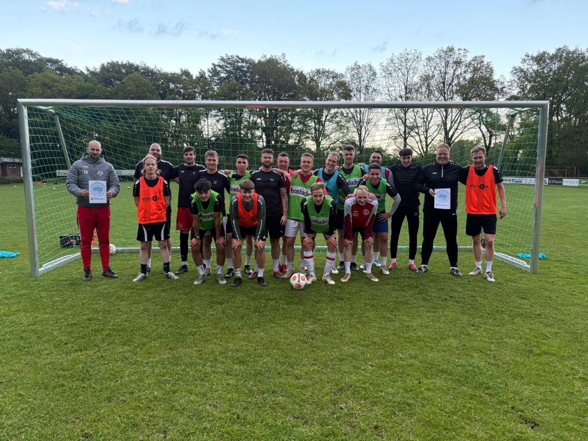 Gruppe von jungen Menschen, die vor einemneuen Fußballtor stehen.