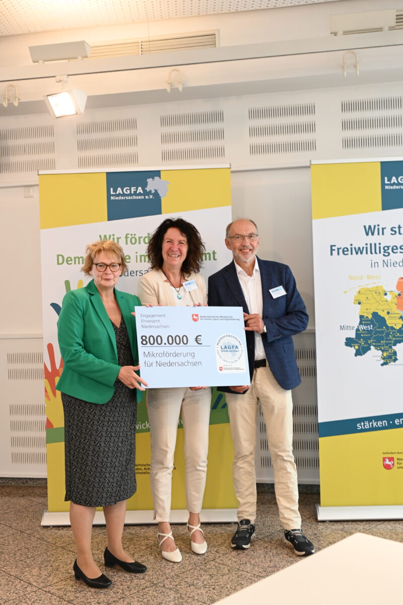 drei menschen mit einem großen symbolischen förderscheck